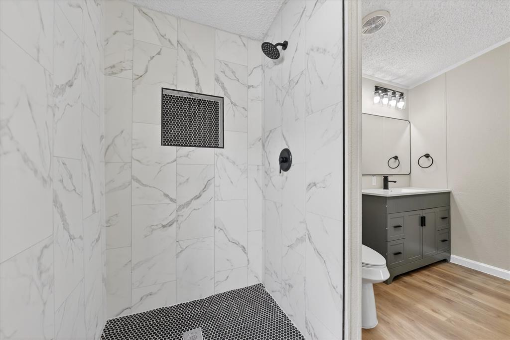 134 Classic Country Court Springtown, TX 76082 - Photo 25 of 35 Walk-in shower with large format white tile walls, black penny tile flooring, and matte black fixtures