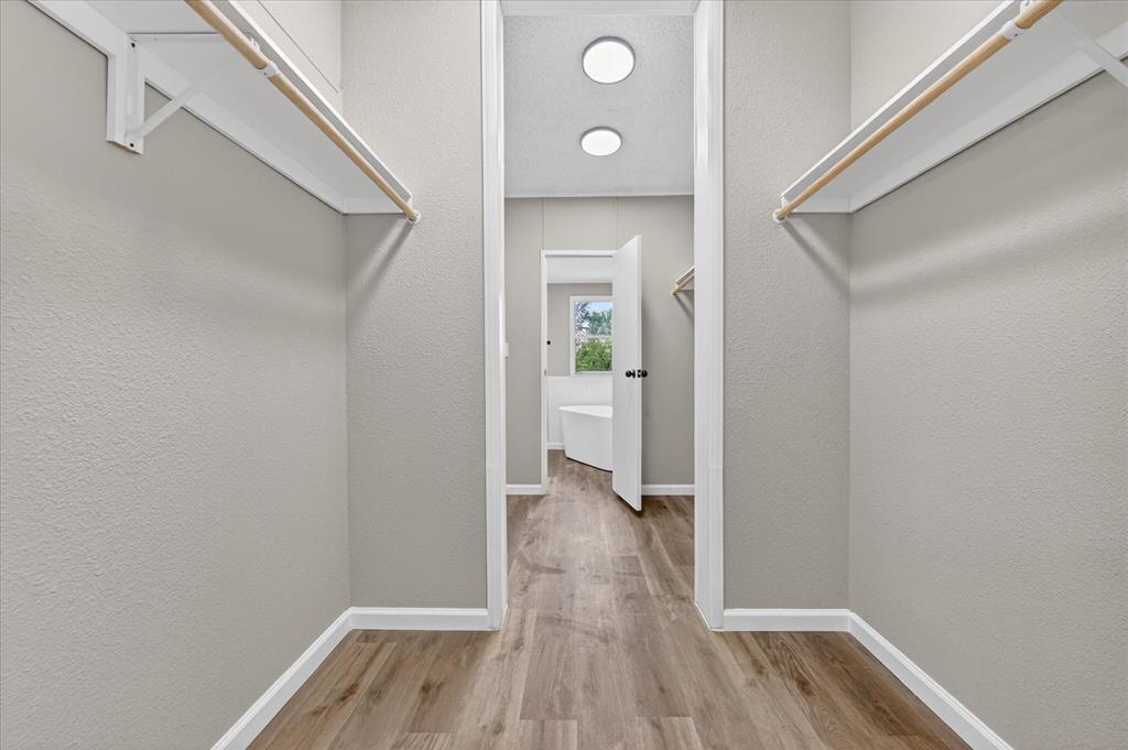 134 Classic Country Court Springtown, TX 76082 - Photo 28 of 35 Walk-through closet with dual hanging rods, wood-finish flooring, and recessed ceiling lighting