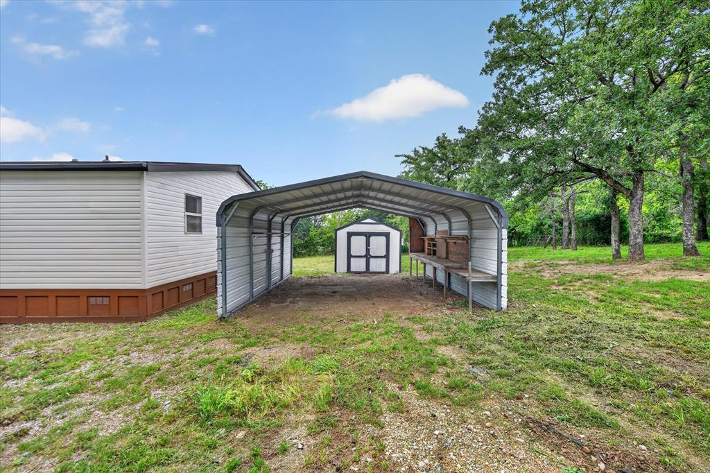 134 Classic Country Court Springtown, TX 76082 - Photo 30 of 35 Carport structure offering covered parking, accompanied by a separate storage shed