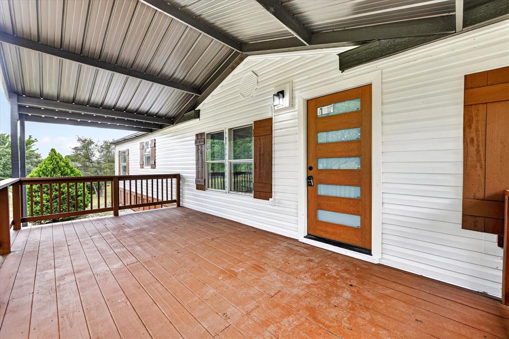 134 Classic Country Court Springtown, TX 76082 - Photo 3 of 35 Expansive covered porch featuring wood flooring, a metal roof, and a wooden railing