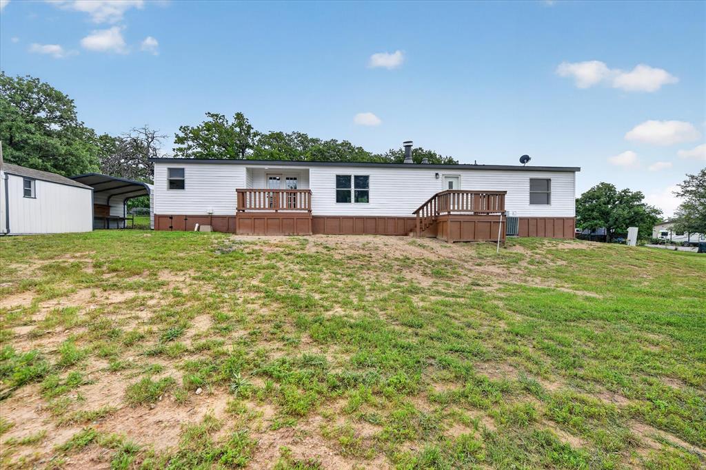 134 Classic Country Court Springtown, TX 76082 - Photo 32 of 35 White exterior with brown trim, featuring two outdoor decks with wood railings and steps