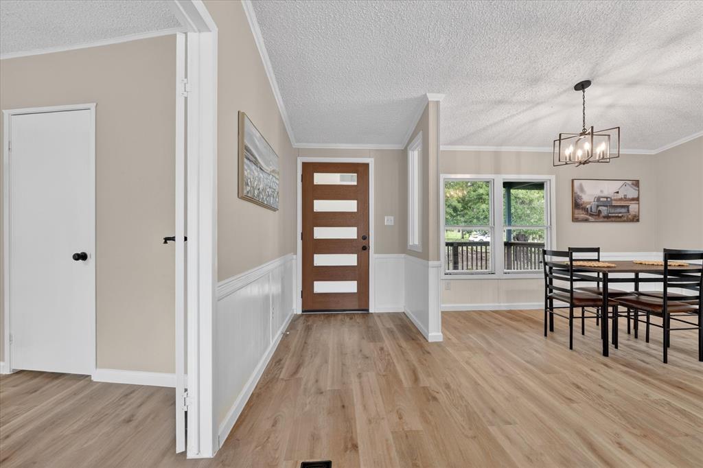 134 Classic Country Court Springtown, TX 76082 - Photo 4 of 35 Entryway featuring a contemporary wooden door with frosted glass panels, wood-finish flooring, white wainscoting, and neutral wall tones