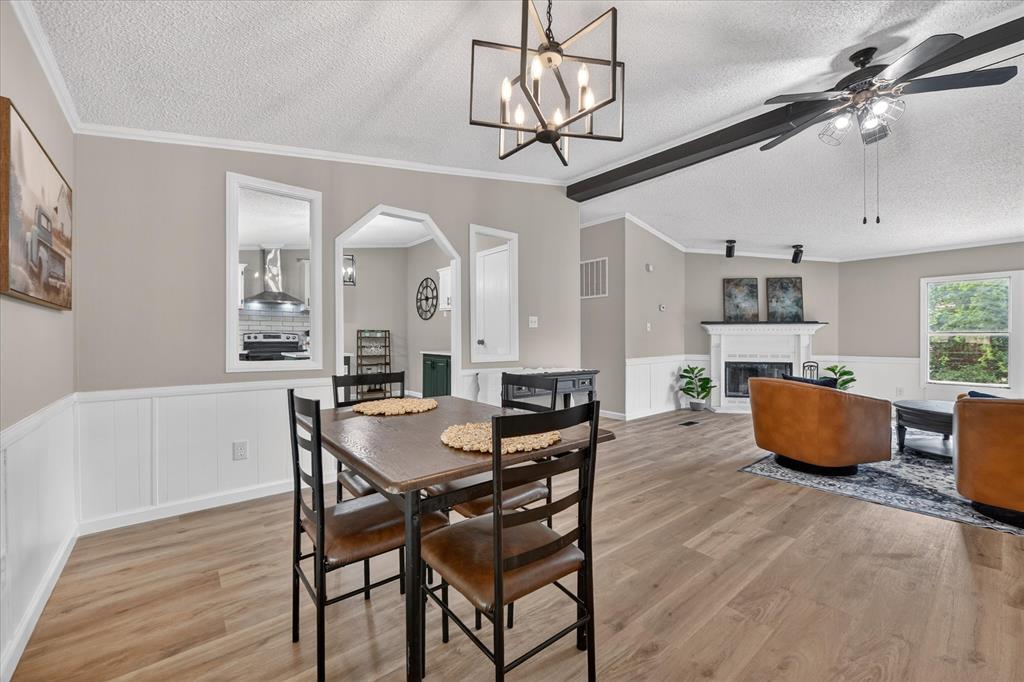 134 Classic Country Court Springtown, TX 76082 - Photo 9 of 35 Expansive open-concept living space featuring wood-finish flooring, wainscoting, and a fireplace with a white mantel