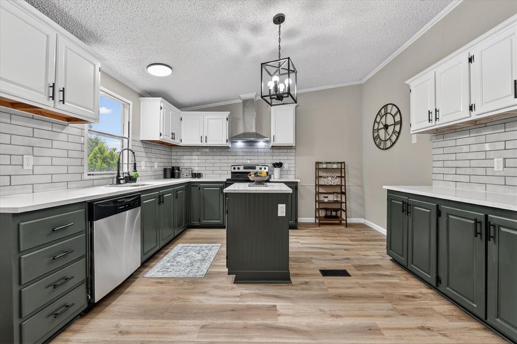 134 Classic Country Court Springtown, TX 76082 - Photo 10 of 35 Spacious kitchen featuring two-tone cabinetry with matte black hardware, light-toned wood-finish flooring, and white subway tile backsplash