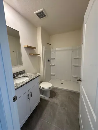 a bathroom with a granite countertop sink a toilet and shower