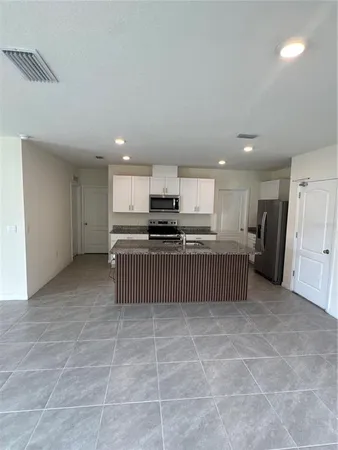 a kitchen with stainless steel appliances granite countertop a stove a sink a refrigerator a microwave and cabinets
