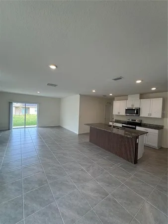 a view of kitchen with kitchen island granite countertop a sink a counter top space and cabinets