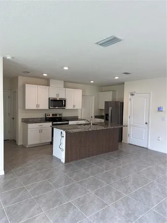 a large kitchen with stainless steel appliances kitchen island granite countertop a stove a sink a refrigerator a microwave and cabinets