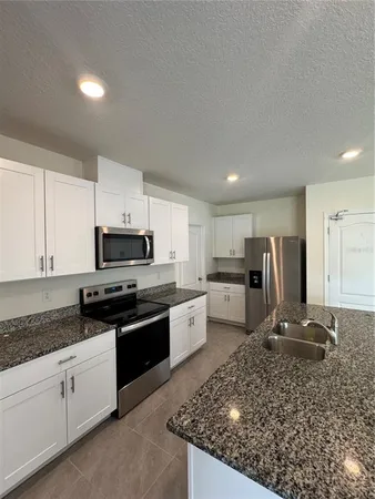 a kitchen with stainless steel appliances granite countertop a sink stove microwave and refrigerator