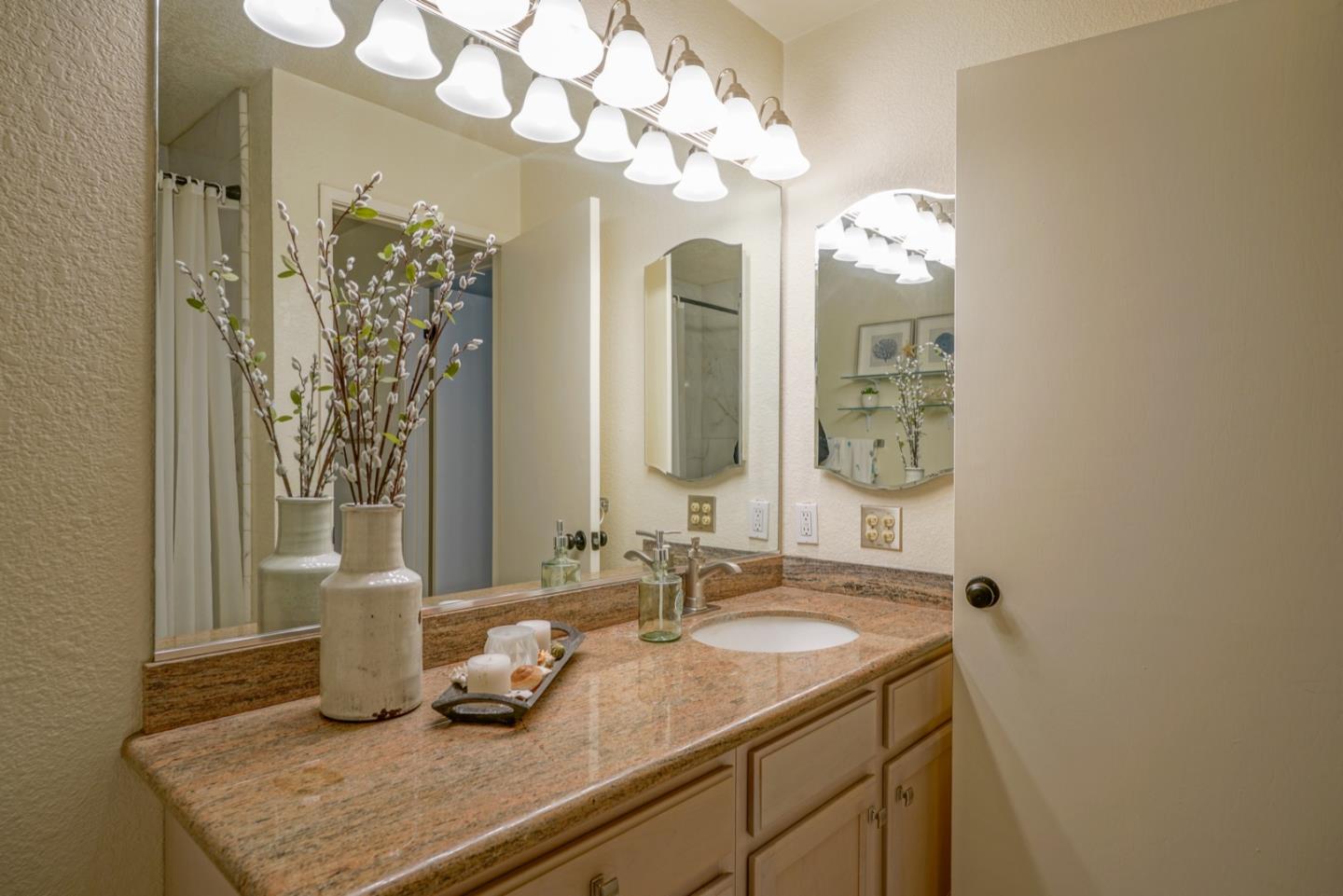 1 Surf Way, Unit 125 Monterey, CA 93940 - Photo 14 of 36 a bathroom with a granite countertop sink a large mirror and a shower
