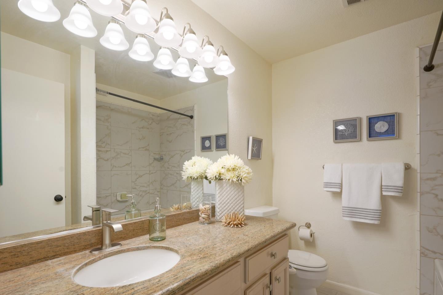 1 Surf Way, Unit 125 Monterey, CA 93940 - Photo 17 of 36 a bathroom with a granite countertop sink a toilet and a mirror