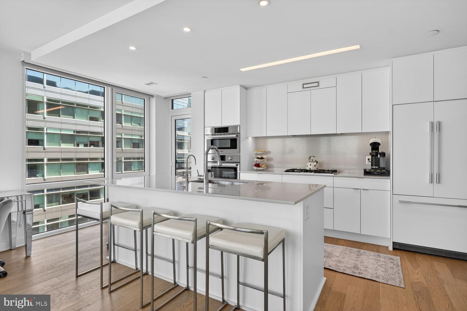 37 L Street Southeast, Unit 802 Washington, DC 20003 - Photo 3 of 23 a kitchen with stainless steel appliances granite countertop a stove top oven a sink a dining table and chairs with wooden floor