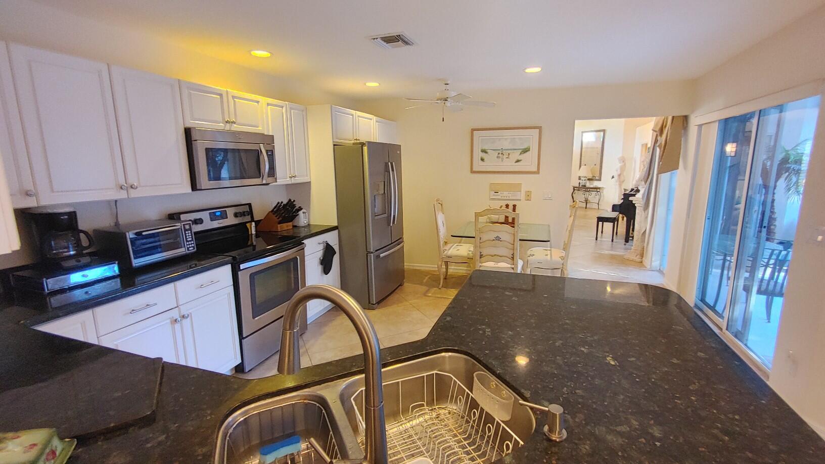 16461 Riverwind Drive Jupiter, FL 33477 - Photo 17 of 45 a kitchen with stainless steel appliances a refrigerator a sink a stove cabinets and a dining table