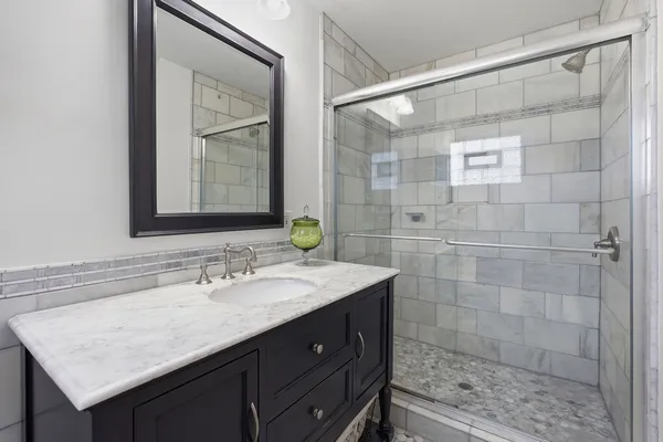 a bathroom with a sink shower and a mirror