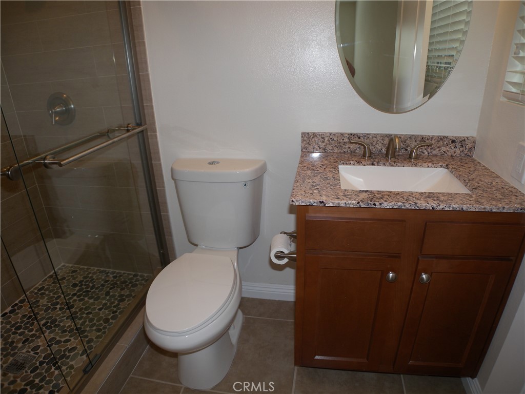 21632 Brookhurst Street, Unit B Huntington Beach, CA 92646 - Photo 12 of 17 a bathroom with a granite countertop toilet sink and mirror