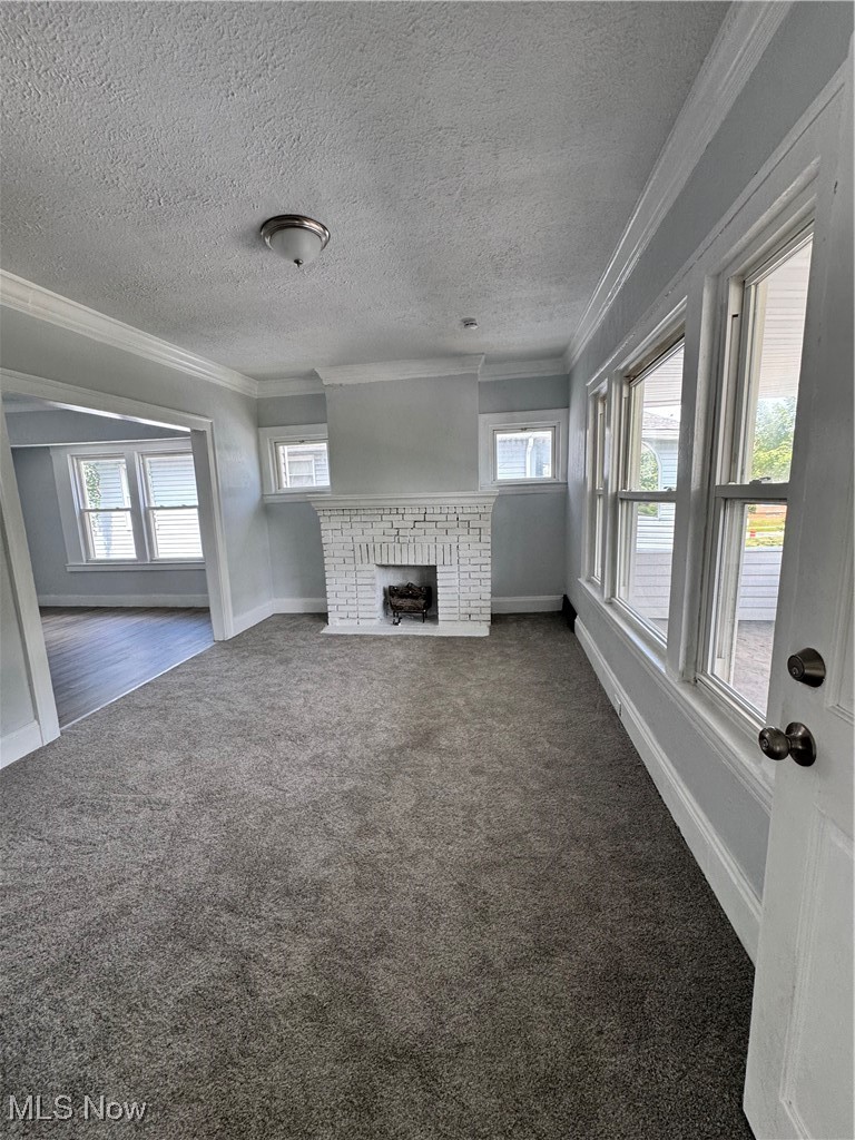 3624 East 118th Street Cleveland, OH 44105 - Photo 30 of 49 Unfurnished living room with crown molding, dark colored carpet, a fireplace, and a textured ceiling