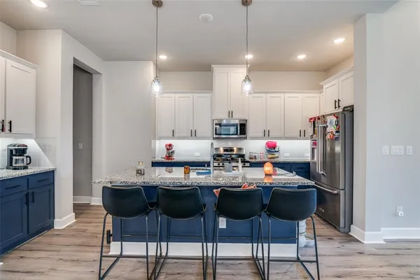 a kitchen with a dining table chairs refrigerator and microwave