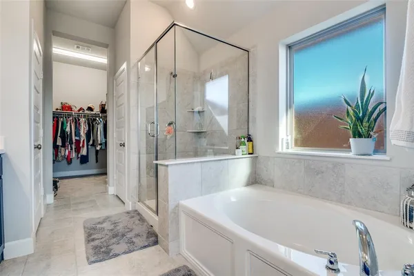 a bathroom with a tub a mirror and a shower