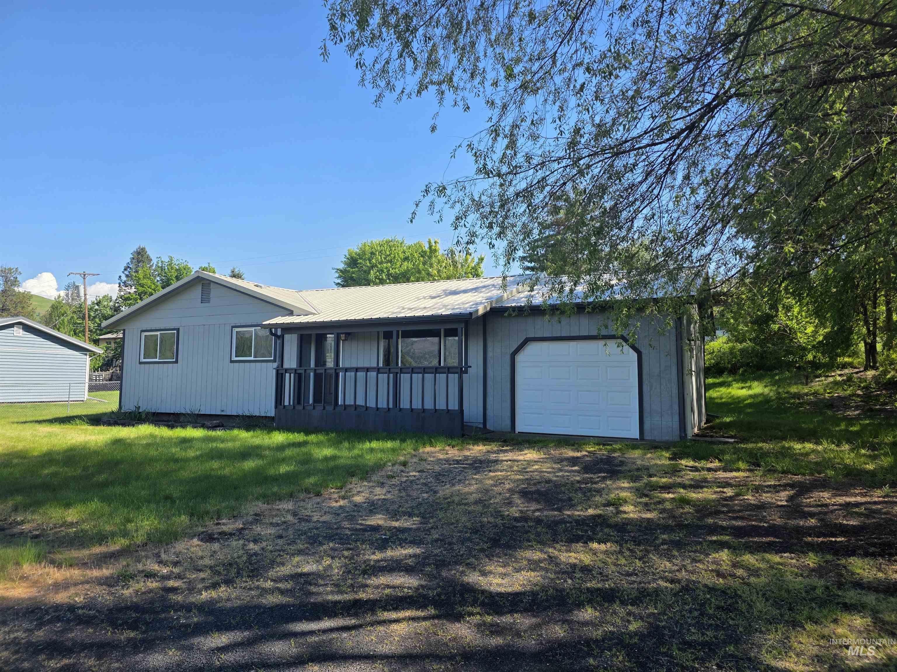 310 Fir Road Kamiah, ID 83536 - Photo 1 of 32 Exterior featuring light blue siding, a covered porch with dark railing, and an attached garage with a white overhead door