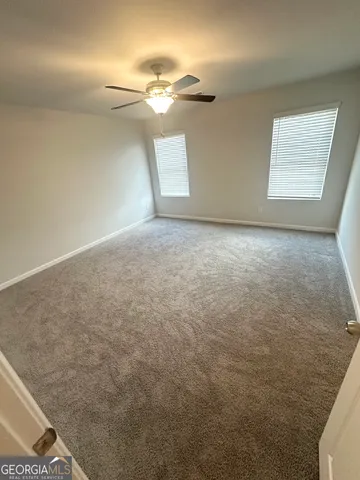 en empty room with windows and ceiling fan