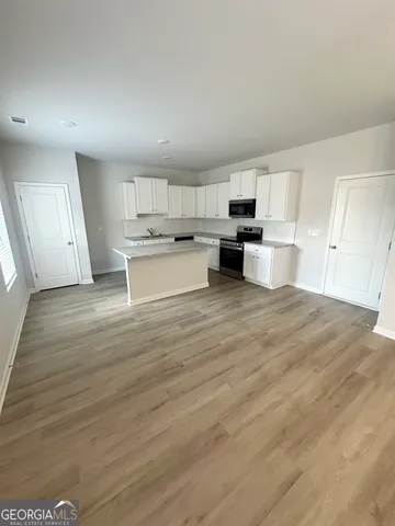a view of a kitchen with kitchen island a sink wooden floor and counter top space