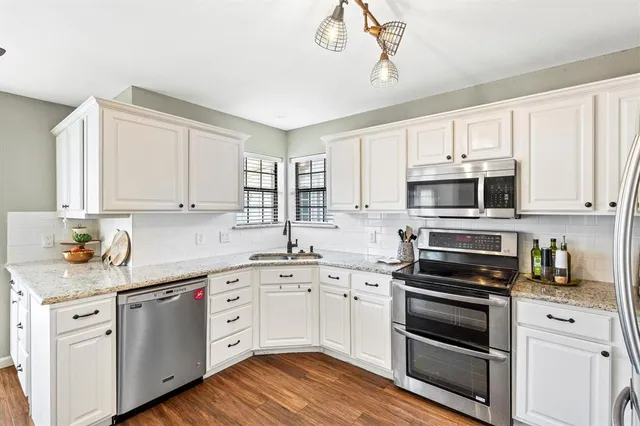 a kitchen with cabinets stainless steel appliances a sink and wooden floor