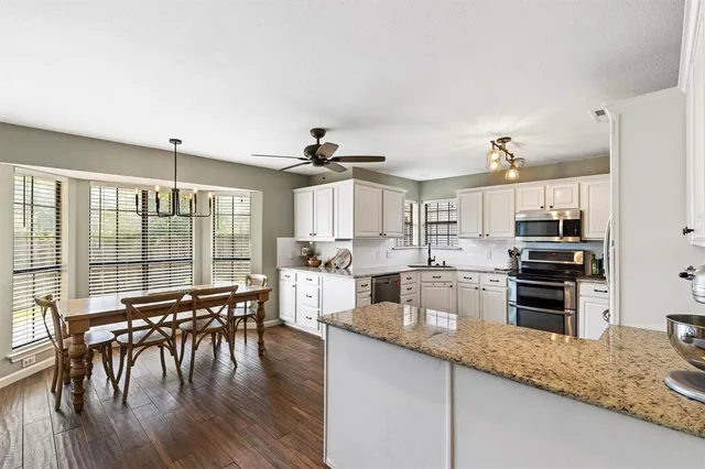 a open kitchen with granite countertop a stove top oven a sink a dining table and chairs