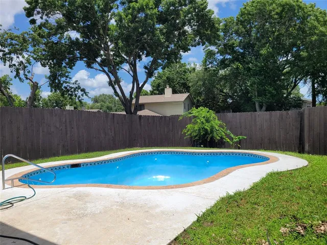 a view of a backyard with a small pool and wooden fence