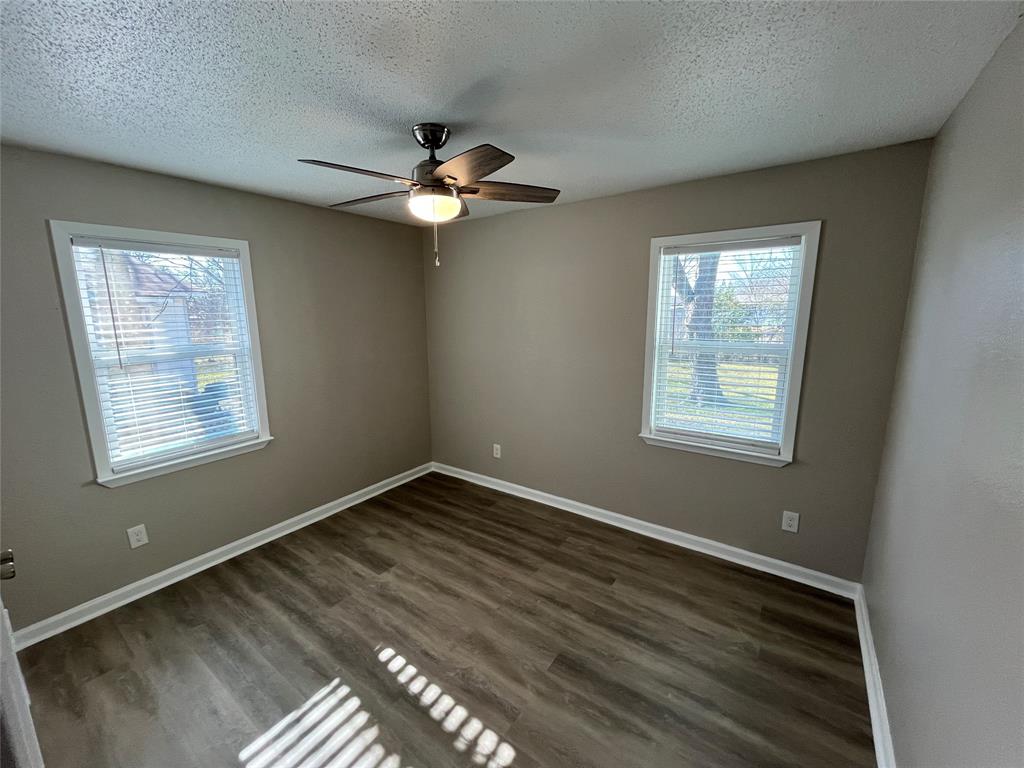 1125 Rancho Drive Mesquite, TX 75149 - Photo 15 of 23 Unfurnished room with dark wood-style flooring, ceiling fan, a textured ceiling, and healthy amount of natural light