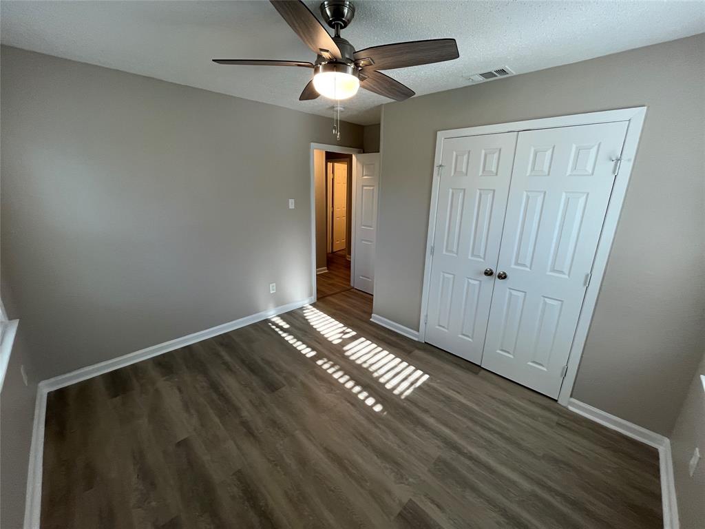 1125 Rancho Drive Mesquite, TX 75149 - Photo 16 of 23 Unfurnished bedroom with dark wood-style flooring, a closet, a ceiling fan, and a textured ceiling