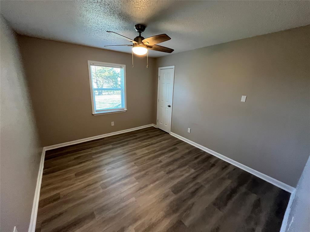 1125 Rancho Drive Mesquite, TX 75149 - Photo 17 of 23 Empty room featuring a textured ceiling, dark wood finished floors, and a ceiling fan