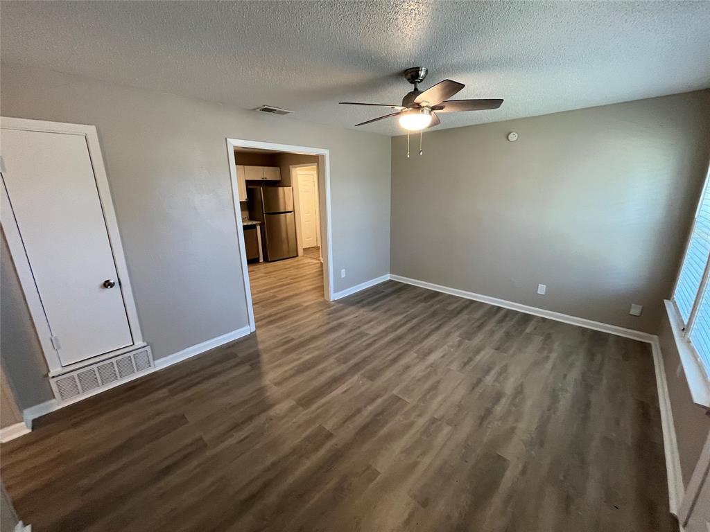 1125 Rancho Drive Mesquite, TX 75149 - Photo 4 of 23 Unfurnished bedroom with freestanding refrigerator, a textured ceiling, dark wood-style flooring, and a ceiling fan