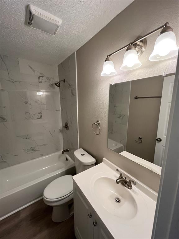 1125 Rancho Drive Mesquite, TX 75149 - Photo 10 of 23 Full bathroom with washtub / shower combination, vanity, a textured wall, a textured ceiling, and dark wood finished floors