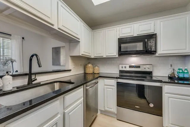 a kitchen with stainless steel appliances granite countertop a sink a stove and microwave