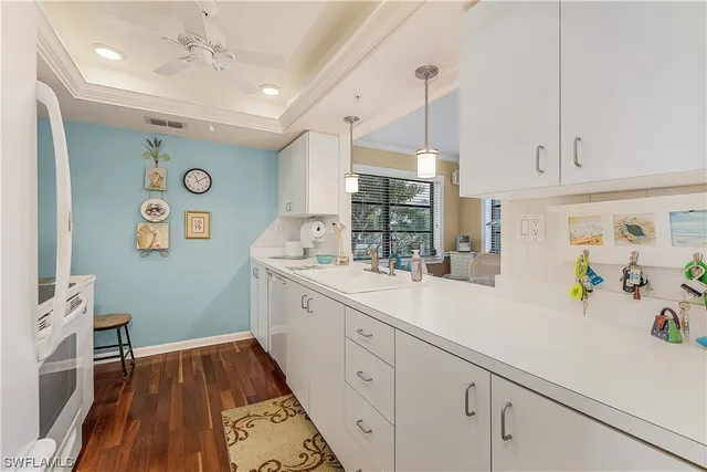 a large white kitchen with a sink and wooden floor