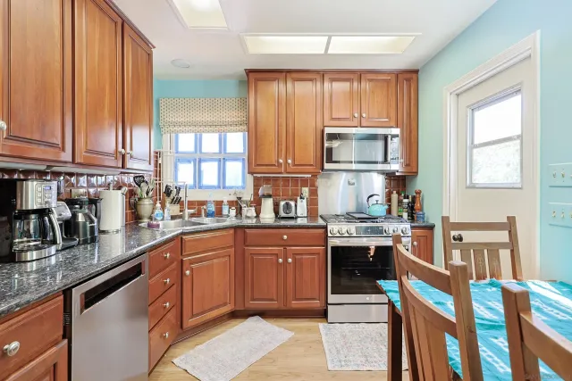 a kitchen with stainless steel appliances granite countertop a stove top oven a sink dishwasher and cabinets with wooden floor