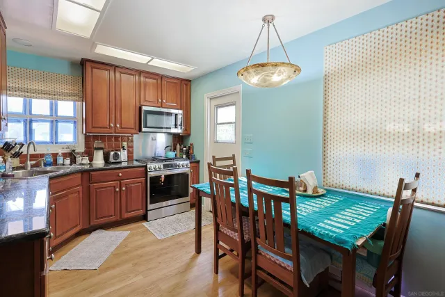 a kitchen with granite countertop stainless steel appliances a stove a sink a dining table and chairs