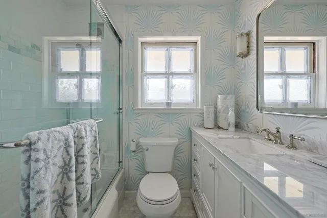 a bathroom with a granite countertop toilet a sink a mirror and a window