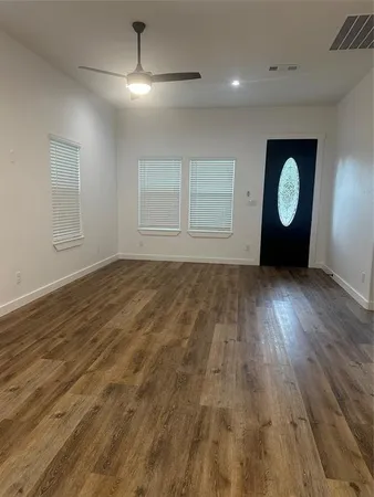 an empty room with wooden floor and windows