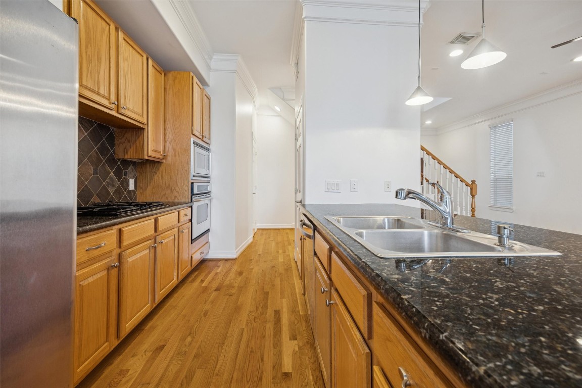 3322 Garden Crest Lane Houston, TX 77018 - Photo 13 of 31 This kitchen features sleek granite countertops, a double sink, stainless steel appliances, and warm wooden cabinetry. It opens into a bright space with recessed lighting and hardwood floors, adding a modern touch.