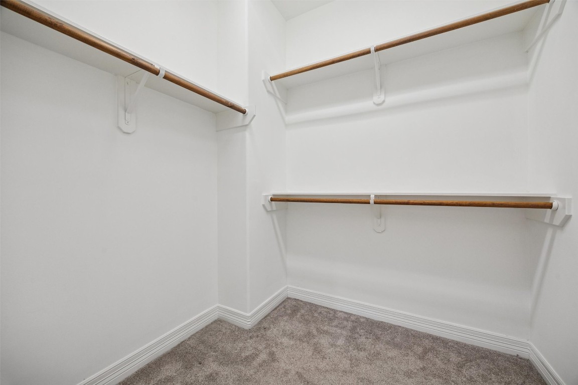 3322 Garden Crest Lane Houston, TX 77018 - Photo 19 of 31 The Primary walk-in closet with multiple wooden hanging rods and white walls, perfect for ample clothing storage. The floor is carpeted, adding warmth and comfort.
