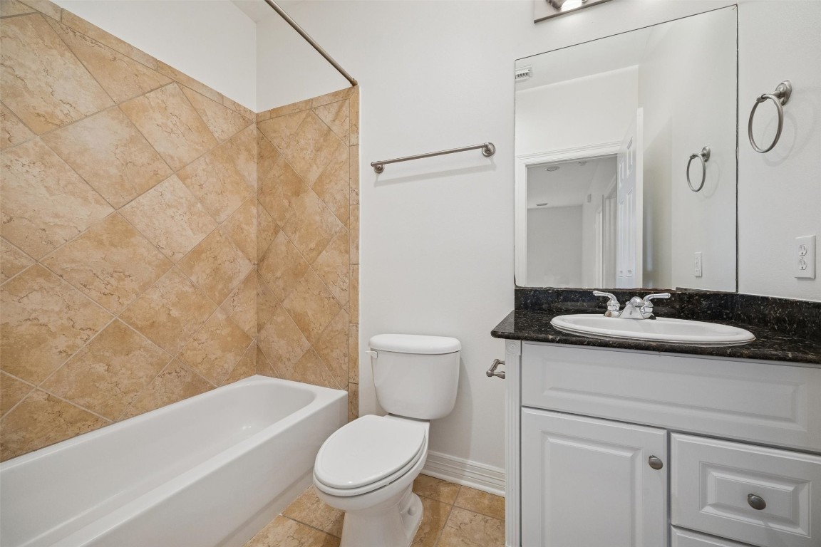 3322 Garden Crest Lane Houston, TX 77018 - Photo 21 of 31 This bathroom features a sleek design with beige tile walls surrounding a bathtub, a white vanity with a dark countertop, and a large mirror above the sink.