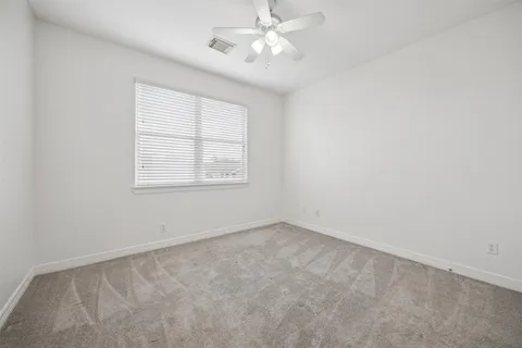 an empty room with a window and a fan