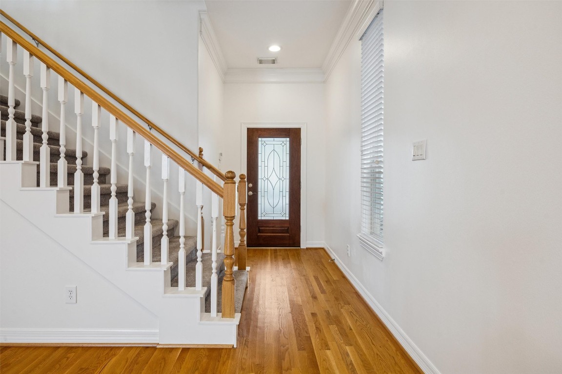 3322 Garden Crest Lane Houston, TX 77018 - Photo 3 of 31 This entryway features a warm wooden floor and a staircase with white balusters and a wooden handrail. The space is bright, with a leaded glass front door.