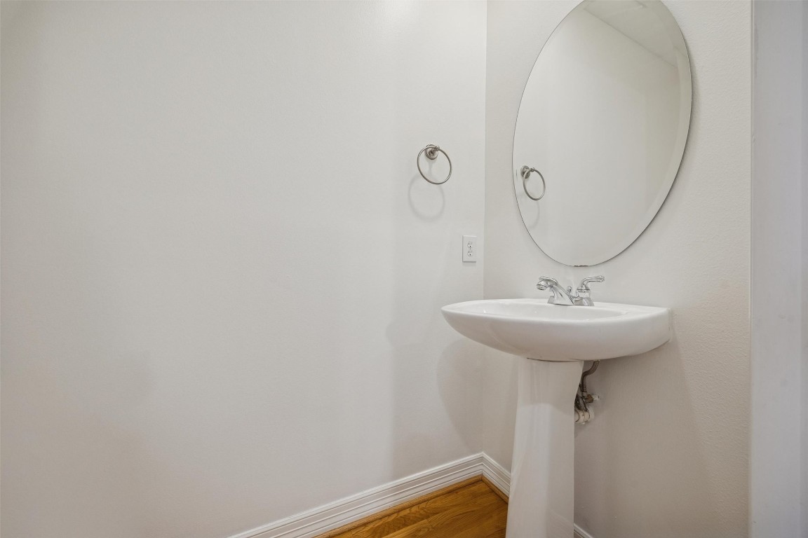 3322 Garden Crest Lane Houston, TX 77018 - Photo 8 of 31 The powder room on the first floor has a pedestal sink, an oval mirror, and hardwood flooring. The space is bright with a clean, minimalist design.