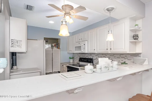 a kitchen with stainless steel appliances kitchen island granite countertop a refrigerator a sink a stove and white cabinets