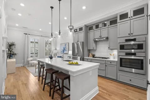 a kitchen with stainless steel appliances granite countertop a stove a sink dishwasher and a refrigerator with wooden floor