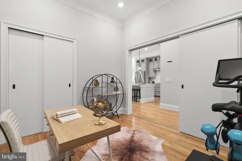 a view of a workspace room with wooden floor table and windows