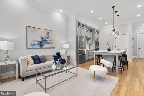 a living room with furniture kitchen view and a wooden floor