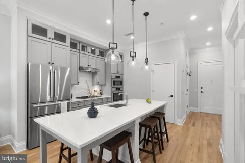 a kitchen with stainless steel appliances a table chairs and refrigerator